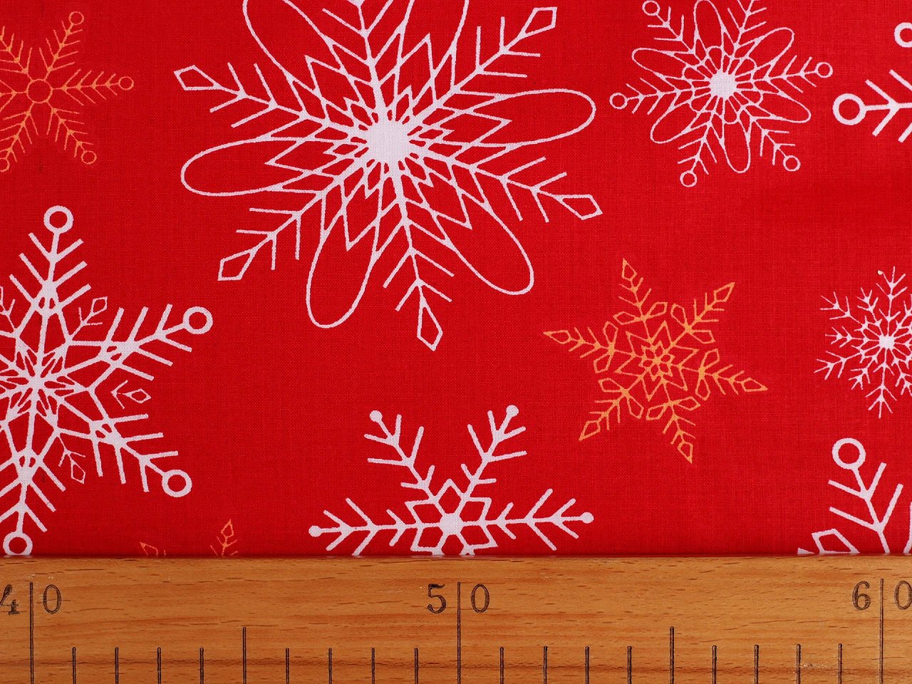 Attēls ar 100% Kokvilnas audums - sniegpārslas uz sarkana fona 125 g/m (DRĪZUMĀ PLAUKTOS) – pieejams Šarlotes audumi