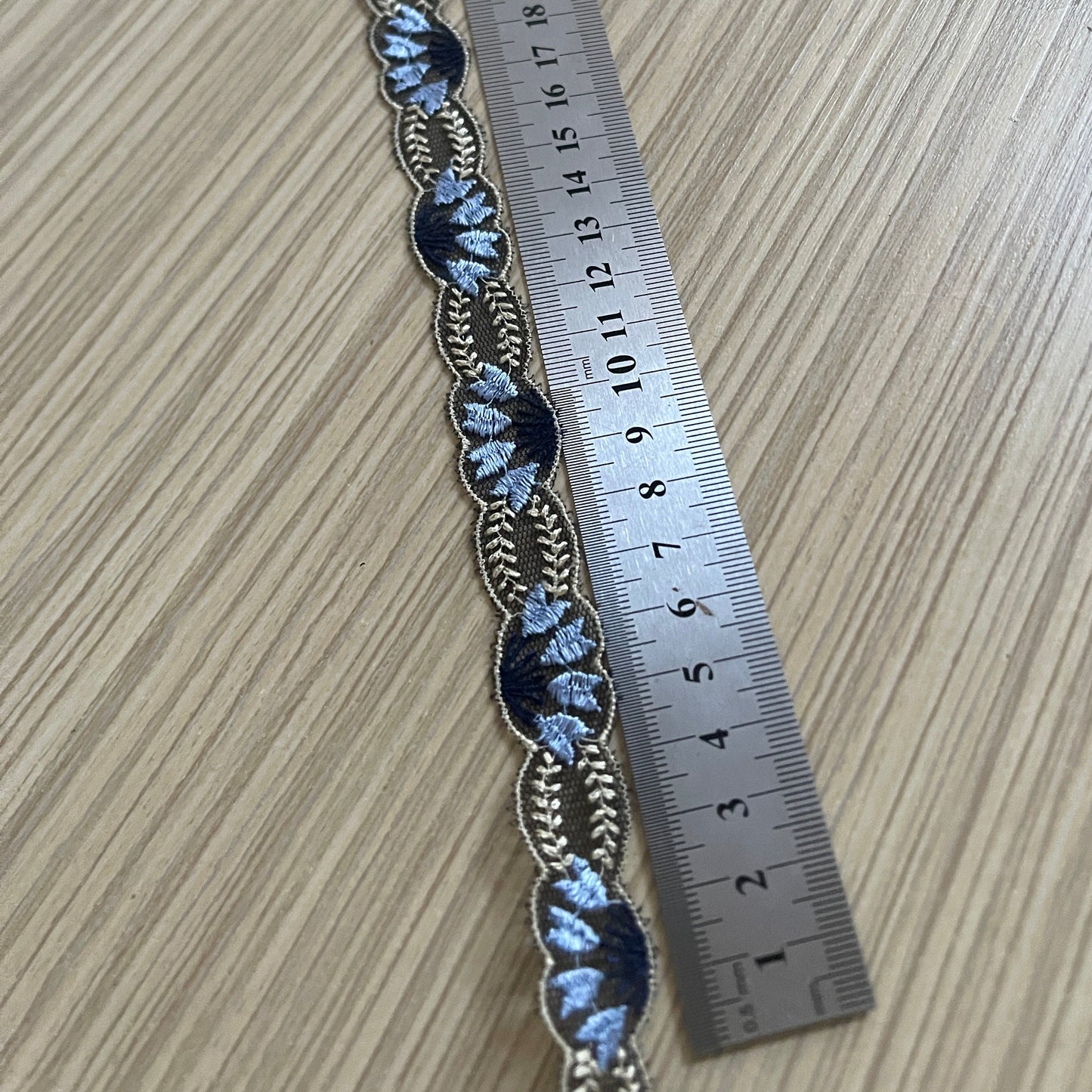 Pilt: tikitud pitslint 2 cm – tumesinine beežide aktsentidega – saadaval Šarlotes audumi