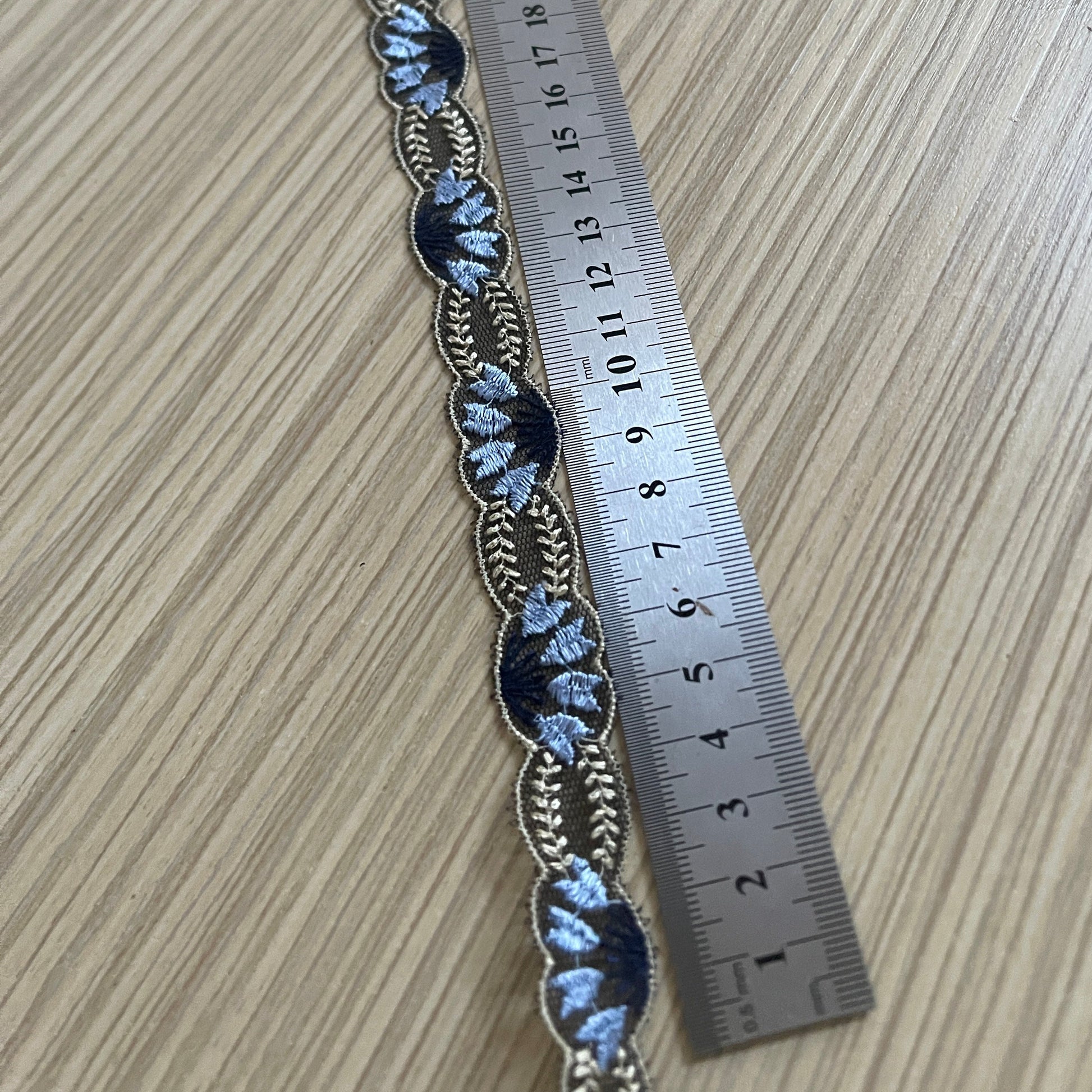 Pilt: tikitud pitslint 2 cm – tumesinine beežide aktsentidega – saadaval Šarlotes audumi