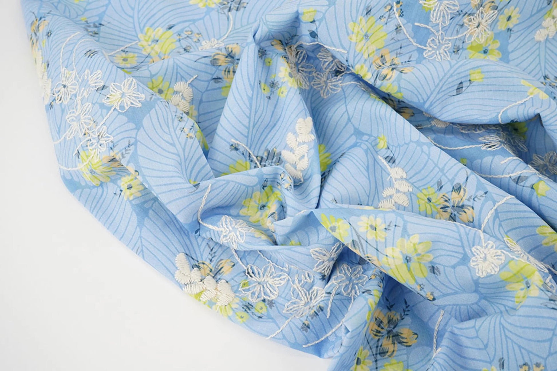 Image de tissu en coton brodé - fleurs jaunes sur fond bleu 115 g/m² – disponible chez Šarlotes audumi